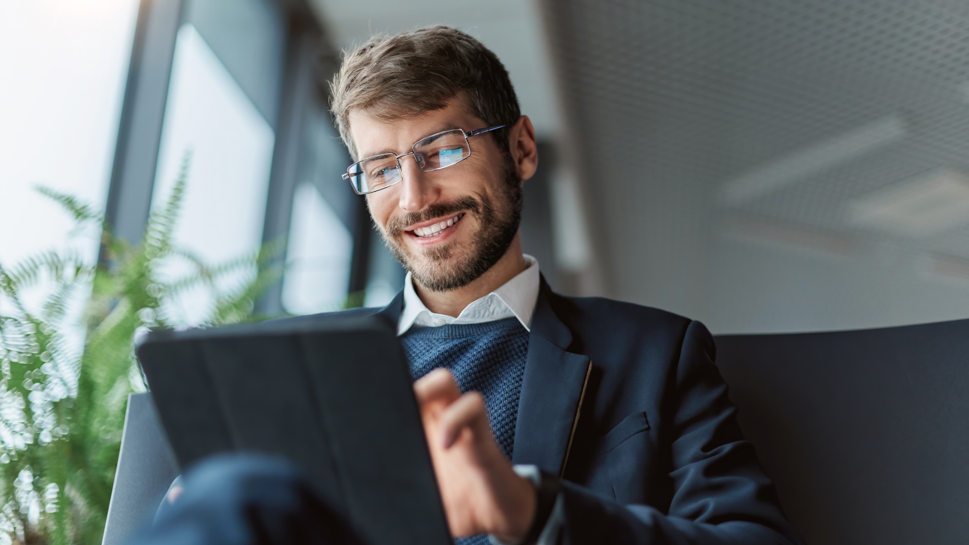 A man smiling while using a tablet.